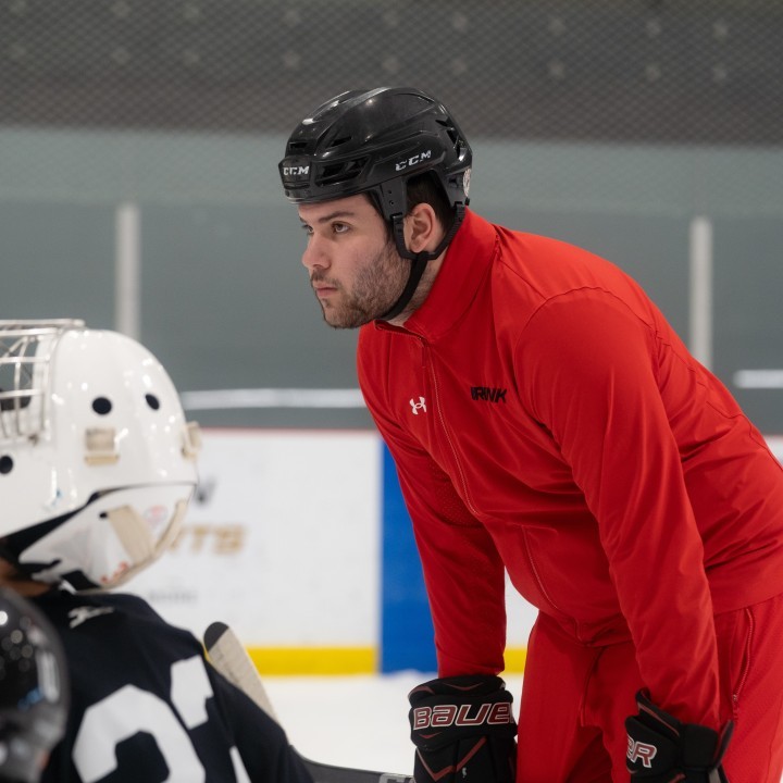 Action shot of Noah Gilbert half-bent over on the ice