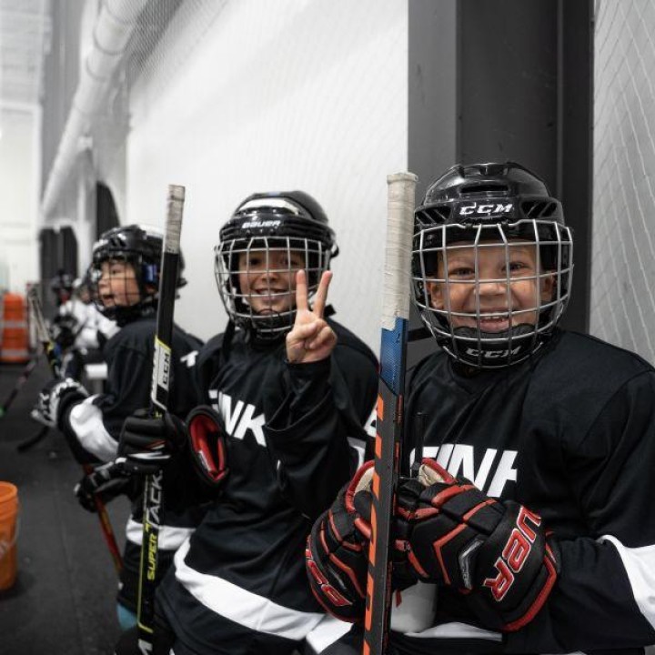 Three smiling children in hockey gear